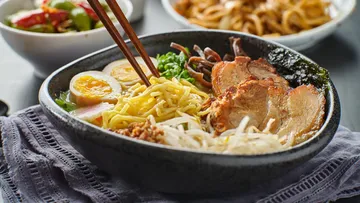 Bowl of ramen and ingredients on a table.