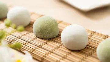 Round mochi balls lie on a bamboo mat.