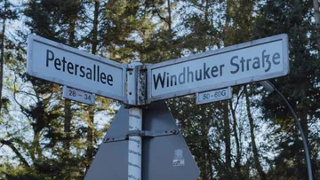 Straßenschild zeigt Petersallee und Windhuker Straße in der Natur.