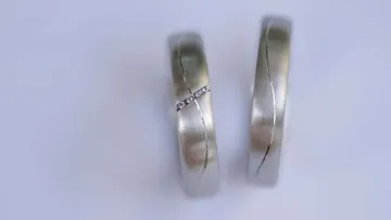 Zwei silberne Ringe liegen nebeneinander auf hellem Untergrund.