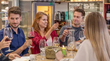 Gruppe von Freunden prostet mit Rotweingläsern in einem Restaurant.