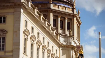 Large historic building with ornamental details, under blue skies.