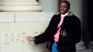 Woman touches a pillar with the date 1443.