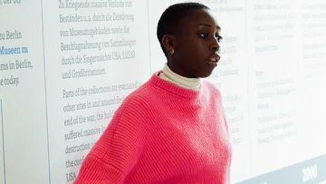 A person stands in front of an information wall and listens.