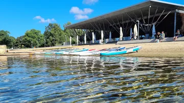 Kayaks lie on the beach, in front of a modern building.