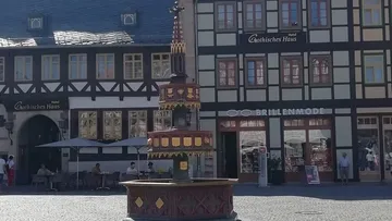 Brunnen steht auf Platz, umgeben von historischen Gebäuden.