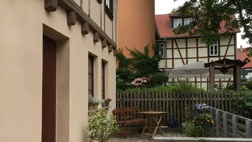 Haus mit Gartenstuhl, umgeben von anderen Gebäuden und Pflanzen.
