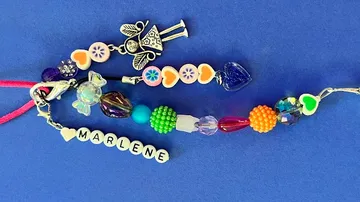 Buntes Armband mit Perlen und einem Anhänger, auf blauem Hintergrund.