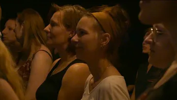 Women look intently, smile in a dark room.
