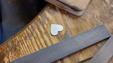 Herzförmiges Metallstück liegt auf einer Holzoberfläche.