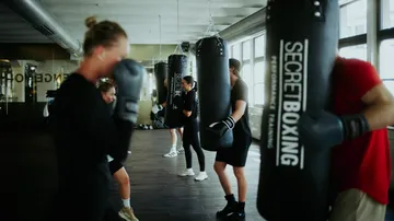Participants train on punching bags in a gym.