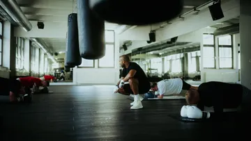 Männer trainieren in einem Fitnessstudio, während ein Trainer anleitet.