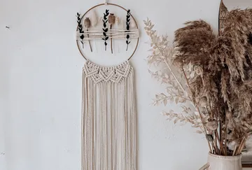 Wall decoration, combined with plants, hangs in front of a wall.