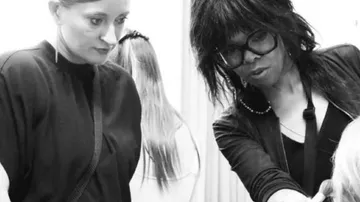 Zwei Frauen betrachten eine Haarstylingtechnik in einem Salon.