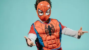 Ein Kind tragend Spiderman-Kostüm macht eine Pose.