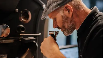 Ein Mann untersucht aufmerksam eine Kaffeemaschine in einer Rösterei.