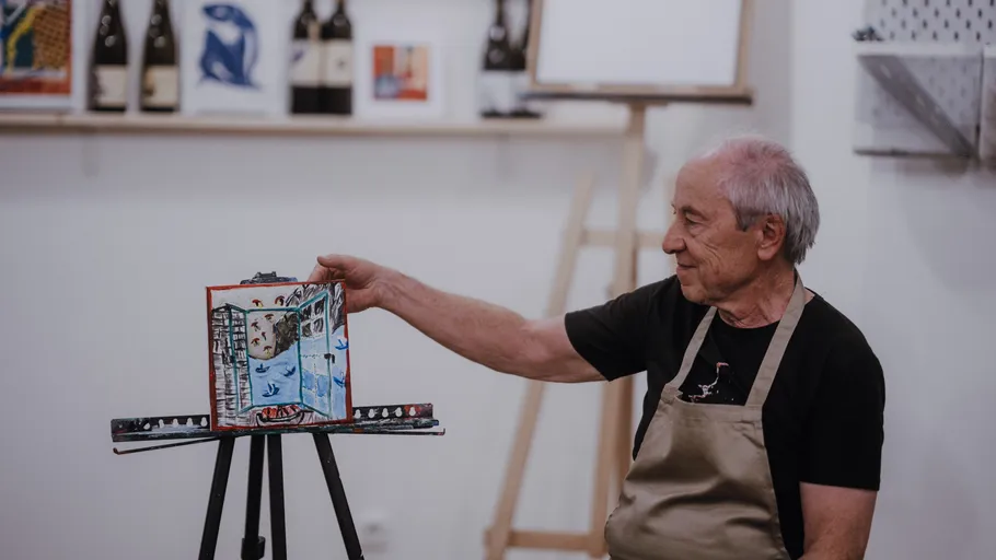 Ein älterer Mann zeigt ein Gemälde auf einer Leinwand.