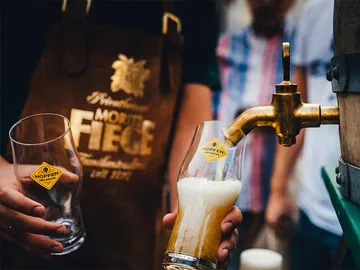 A beer glass is filled under a tap.
