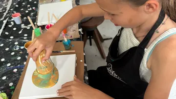 Girl sets a golden color on canvas.