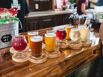 Biergläser stehen auf einem Holzbrett in einer Bar.