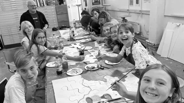 Group kids paint puzzles in a creative space.