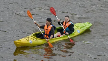 Zwei Personen paddeln gemeinsam in einem grünen Kajak.