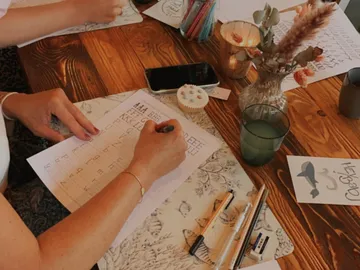 A hand writes on paper surrounded by decoration and snacks.