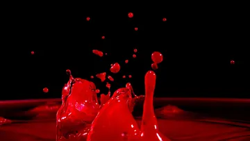 Red liquid splashes in different directions on a black background.