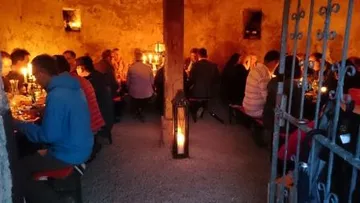 A group is sitting in a room by candlelight.
