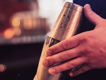 Ein Bartender schüttelt einen Cocktail-Shaker in einer Bar.