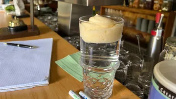 A glass of foam stands on top of another glass.