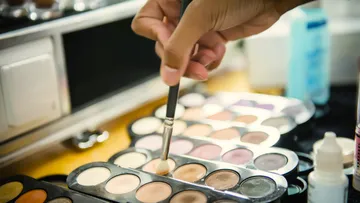 Pinsel nimmt Lidschatten aus einer Palette auf einem Tisch.
