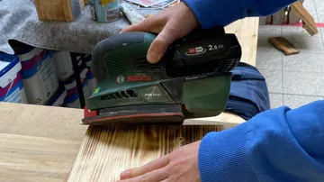 A Bosch grinder smoothes wood surfaces in a workshop.