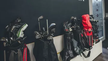 Golfbags stehen an einer Wand in einem Innenraum.