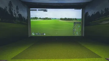 Golf-Simulator zeigt eine virtuelle Golfplatzansicht im Raum.