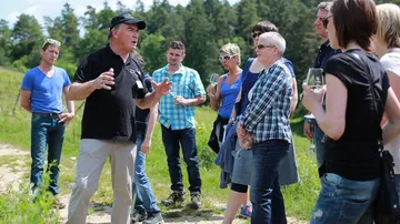 Group of people listen to a man outdoors.
