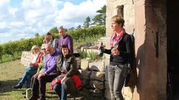 Group of people sitting outside, one person holding drinks.