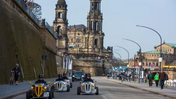 Drei Kleinwagen fahren eine Straße entlang in Dresden.