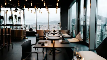 Elegantes Restaurant mit Tischen, Blick auf die Stadt.