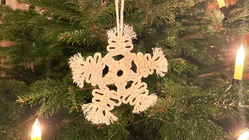 Weißer Schneekristall hängt an einem Weihnachtsbaum.