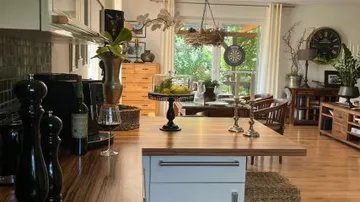 Moderne Küche mit Holzinsel, Pflanzen und Wohnzimmeransicht.