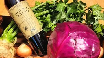 Red cabbage and vegetables with wine bottle on a table.