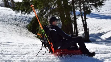 A man rides on a sled in the snow.