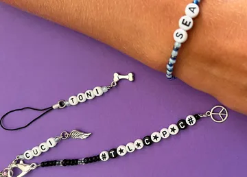 Bunte Armbänder mit personalisierten Buchstaben auf lila Hintergrund.