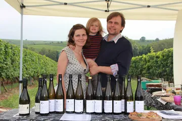 Familie steht an einem Weintisch in Weinbergen.