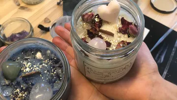 Zwei Kerzen in einer Hand, dekoriert mit Blumen und Kristallen.