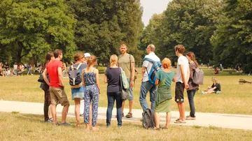Gruppe von Menschen hört einem Redner im Park zu.