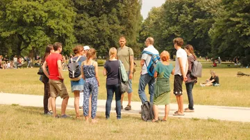 Group of people discussing on a meadow in the park.