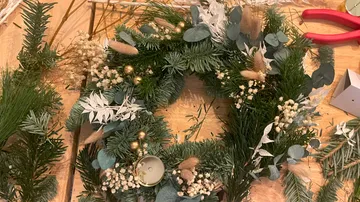 Wreath decorated with dried flowers, arranged on wooden surface.
