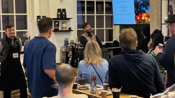 People listen carefully to a speaker in a café.